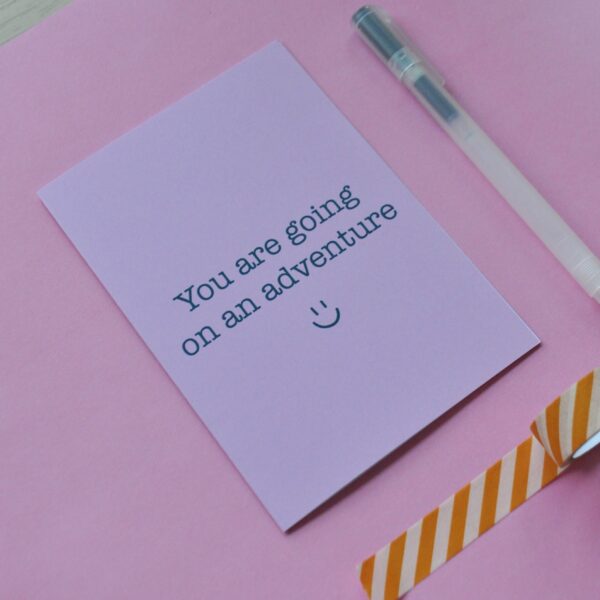 Roze kaart met de tekst 'you are going on an adventure' en een lachend gezichtje eronder.