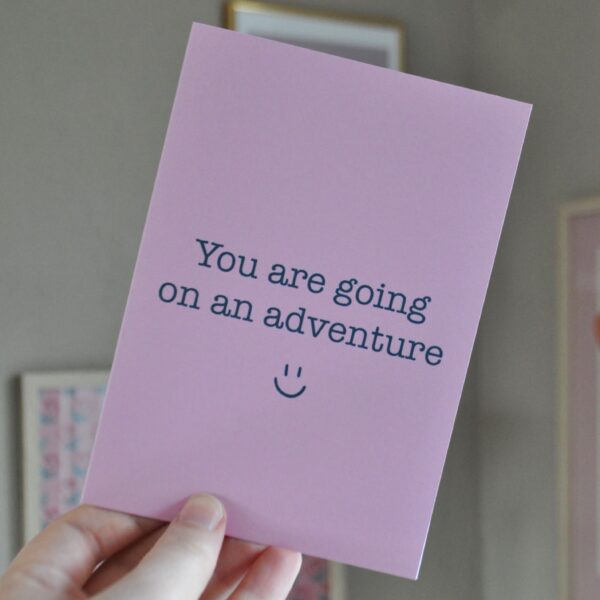 Roze kaart met de tekst 'you are going on an adventure' en een lachend gezichtje eronder.