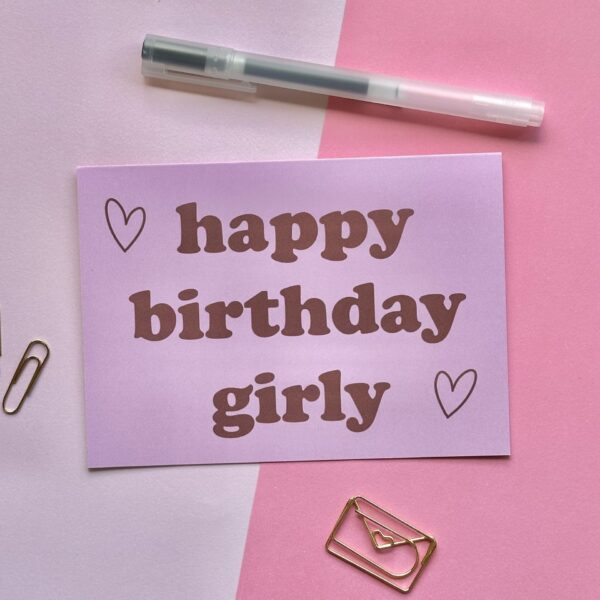 roze verjaardagskaart met rode letters en hartjes en de tekst 'happy birthday girly'