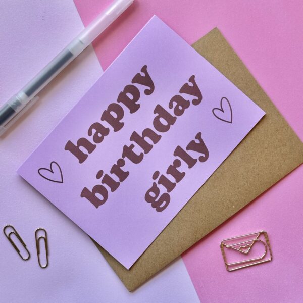 roze verjaardagskaart met rode letters en hartjes en de tekst 'happy birthday girly'